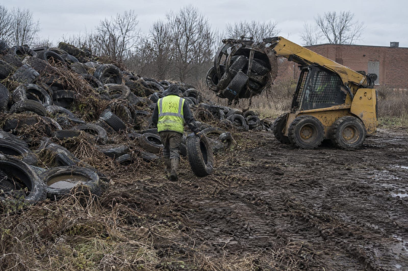A loader clearing a large pile of dumped tires